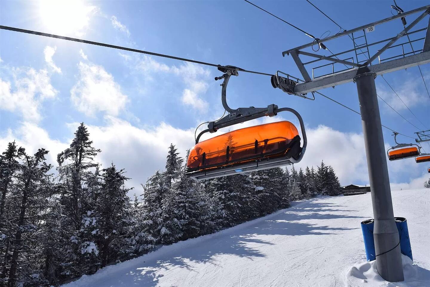 Orange chairlift above snowy trails at Okemo